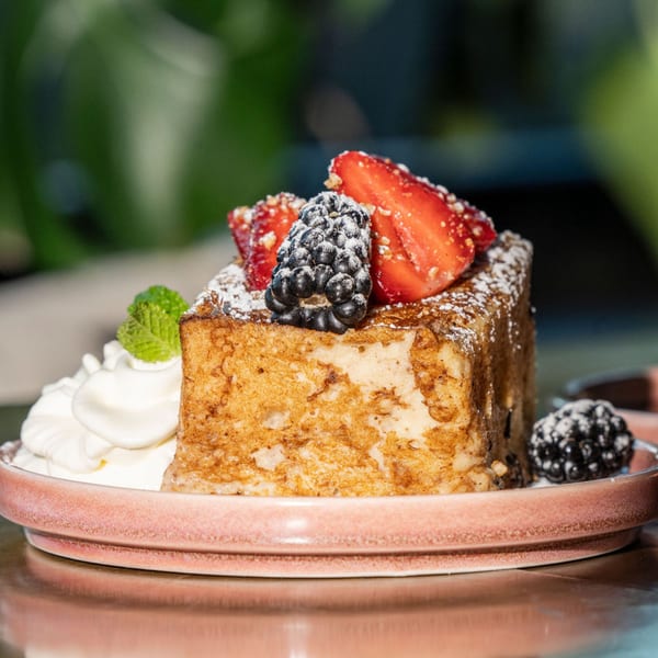 Thick-cut French toast topped with strawberries, blackberries, powdered sugar, and whipped cream.