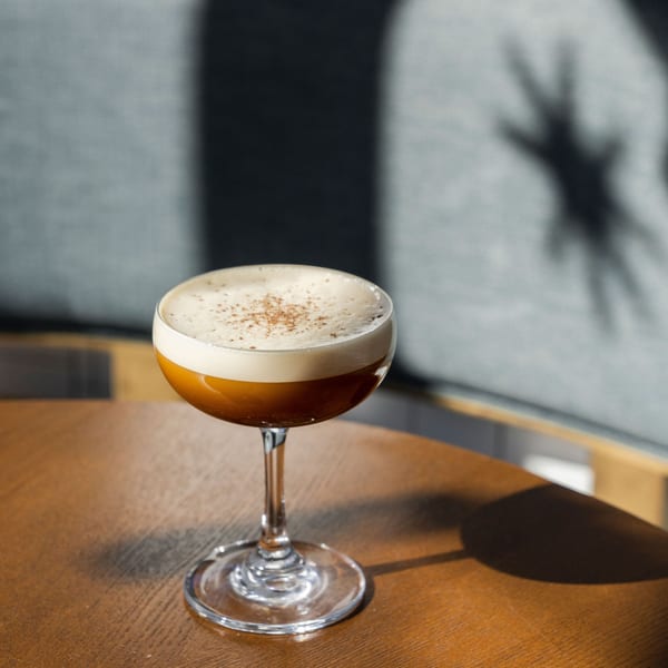 A Paraiso Mexican Restaurant cocktail with foam and spice on a wooden table.